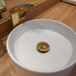 Projekt małej łazienki zakłada połączenie płytek imitujących marmur z bateriami w kolorze złotym. Projekt kawalerki - Studio Architektownia.